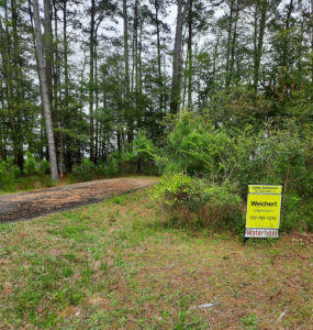Lot 3 with yellow for sale sign and trees in background